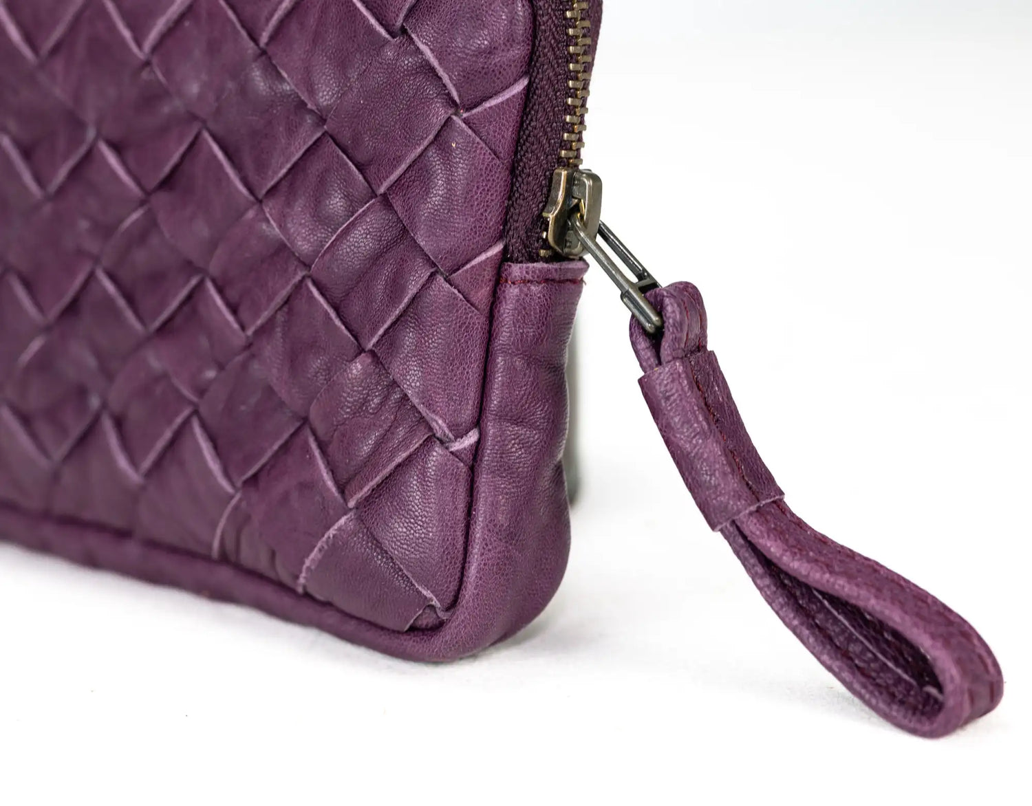 Close-up of a purple quilted handbag with a strap on a white background