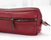 Red leather bag with multiple zippers on a white background