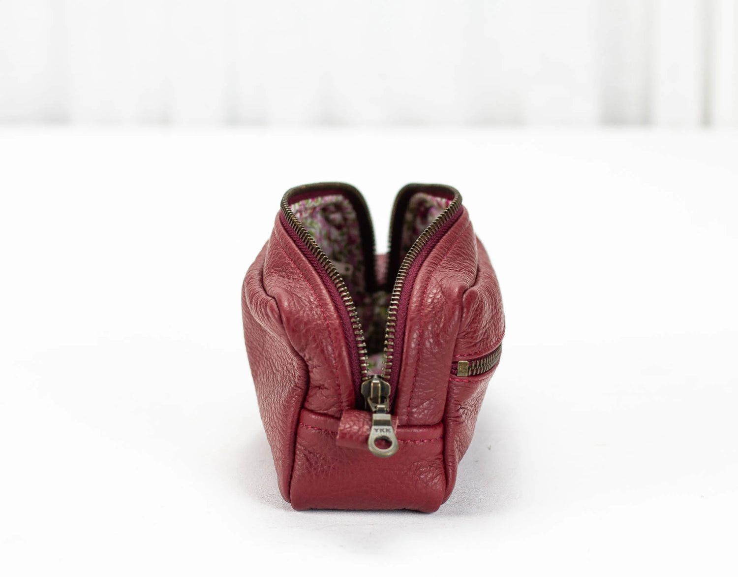 Red leather handbag with a zipper on a white background