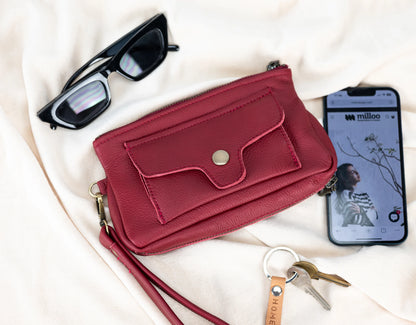 Red wallet with sunglasses, phone, and keys on a light background