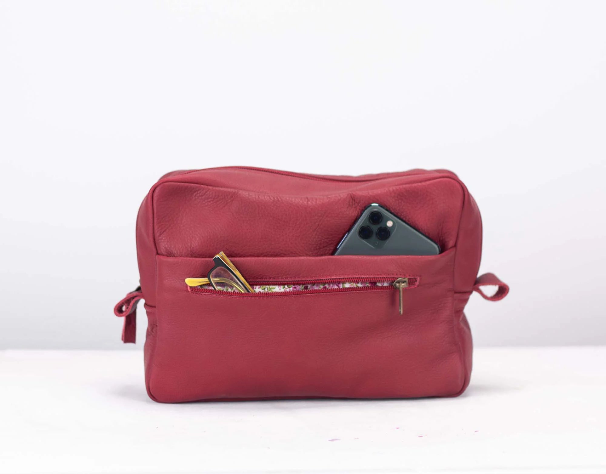 Red travel pouch with items inside on a white background