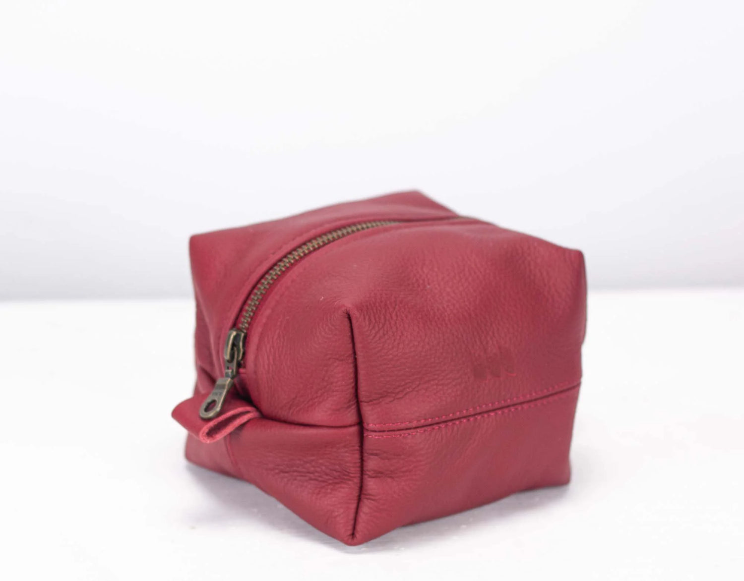 Red leather toiletry bag with a zipper on a white background
