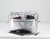Silver pouch with phone, passport, and tablet on a white background