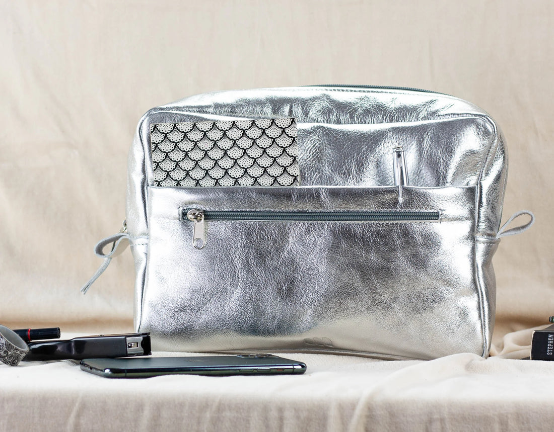 Silver insert bag on a beige surface with a phone and lip gloss visible