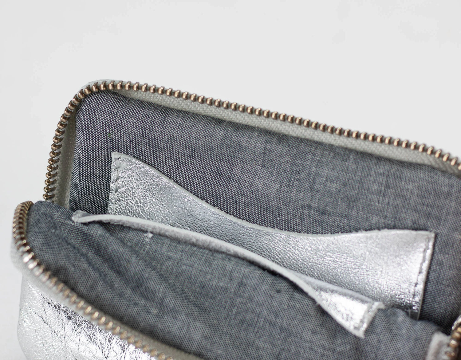 Close-up of a gray pouch with a silver lining on a light gray background