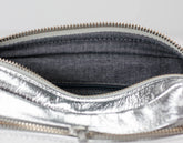 Close-up of a silver metallic pouch with a zipper, showing the interior