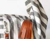 Close-up of a striped bag with leather tassels on a white background