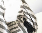 Black tassel keychain attached to a striped garment on a white background