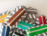 Set of colorful striped bags with zippers on a white background