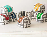 Set of fabric pouches with geometric patterns and colorful zippers on a white surface.