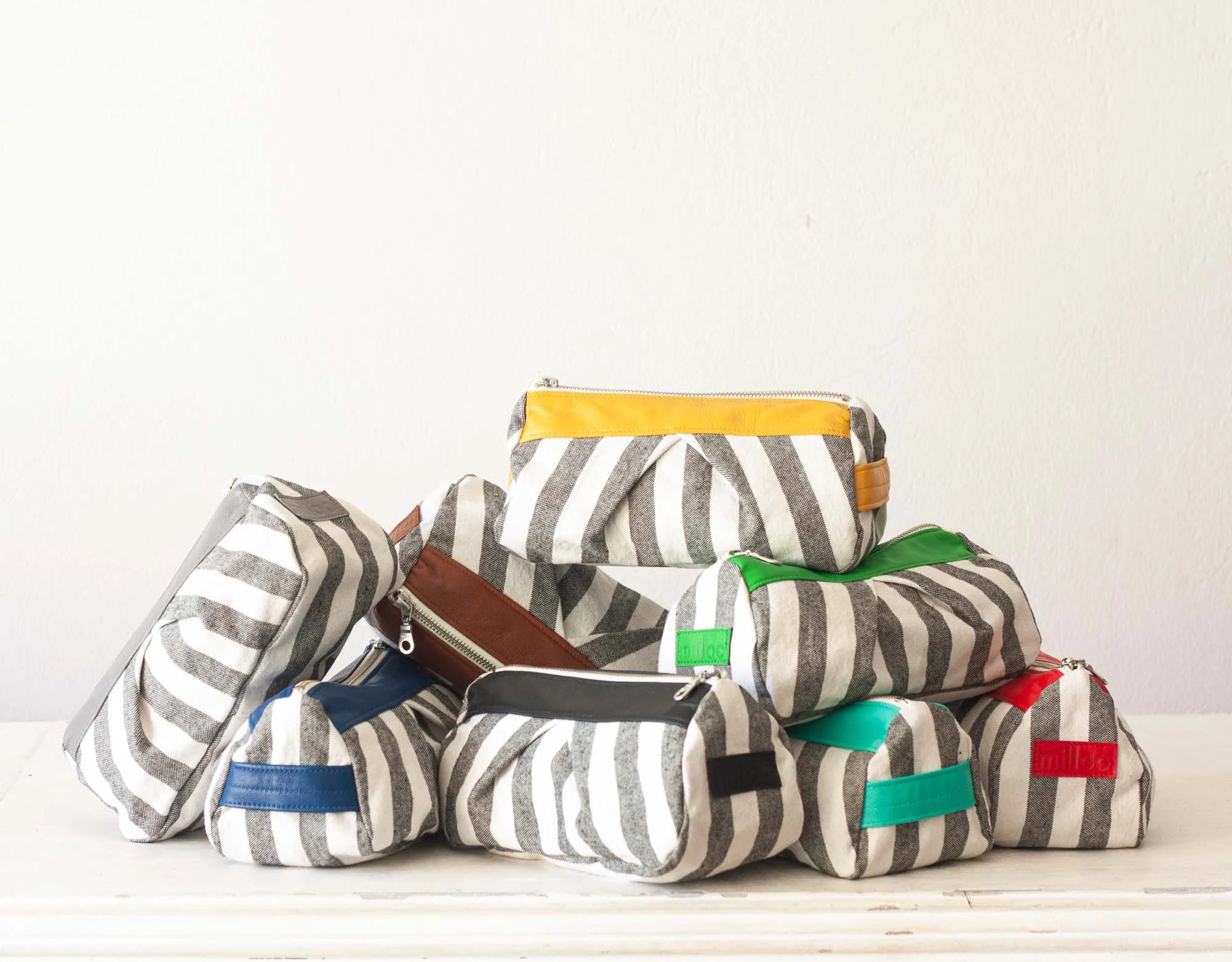 Set of striped fabric pouches with colorful zippers on a white background