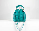 Teal leather handbag with drawstring on a white background