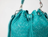 Turquoise woven handbag with drawstring on a light gray background