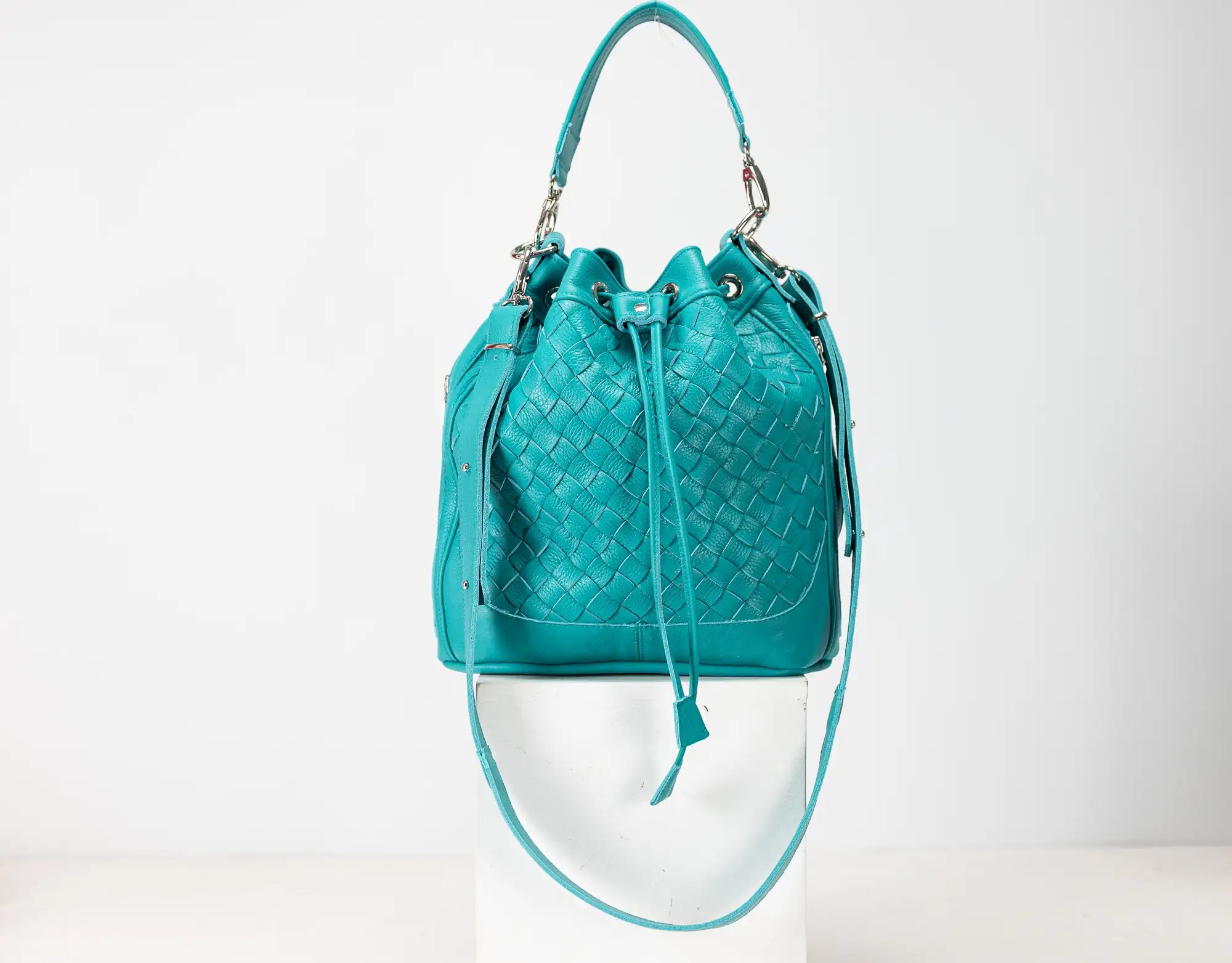Turquoise woven handbag on a white background