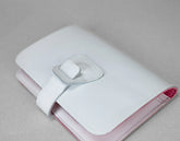 White and pink wallet with a silver buckle on a light gray background