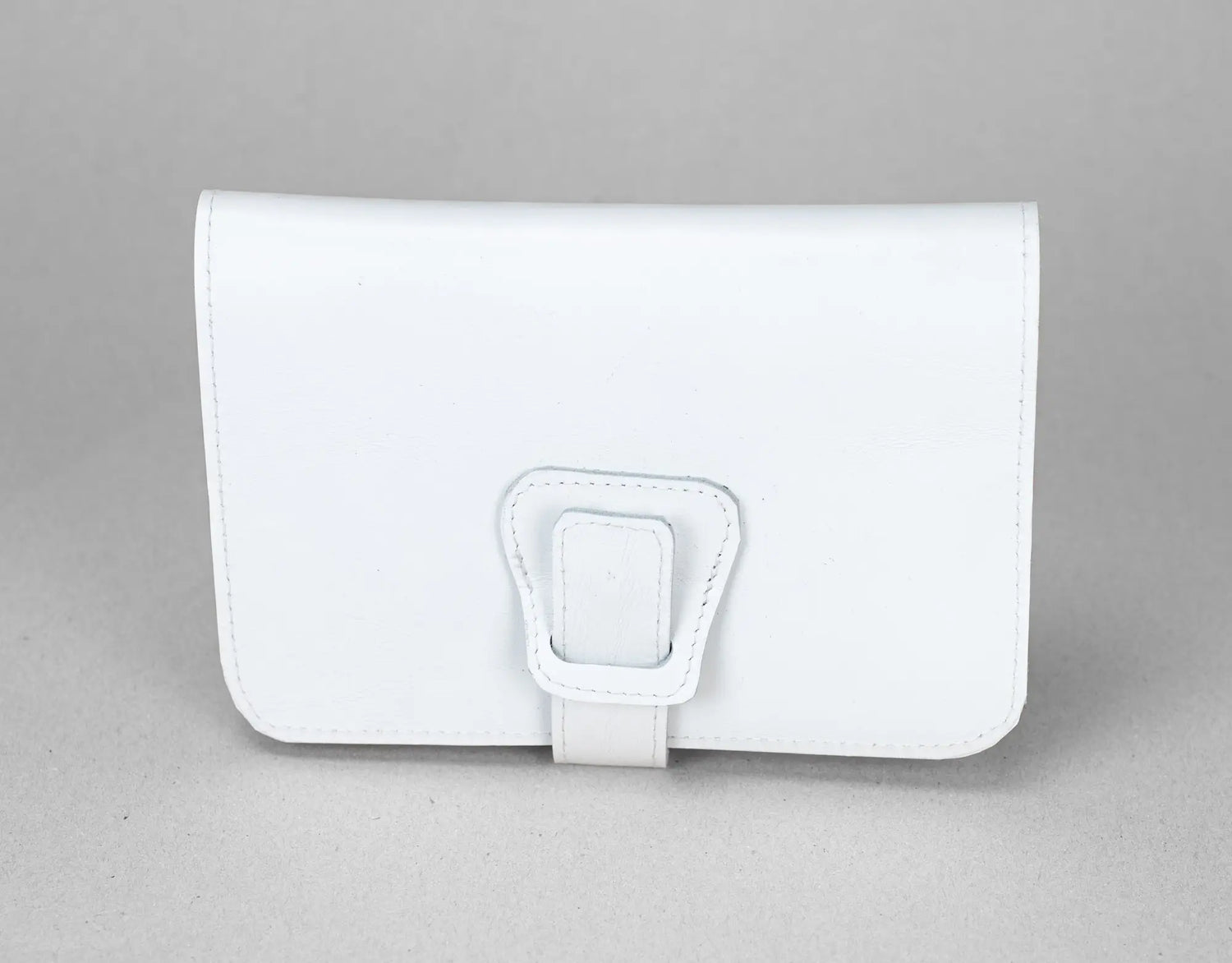 White leather wallet with a buckle on a gray background