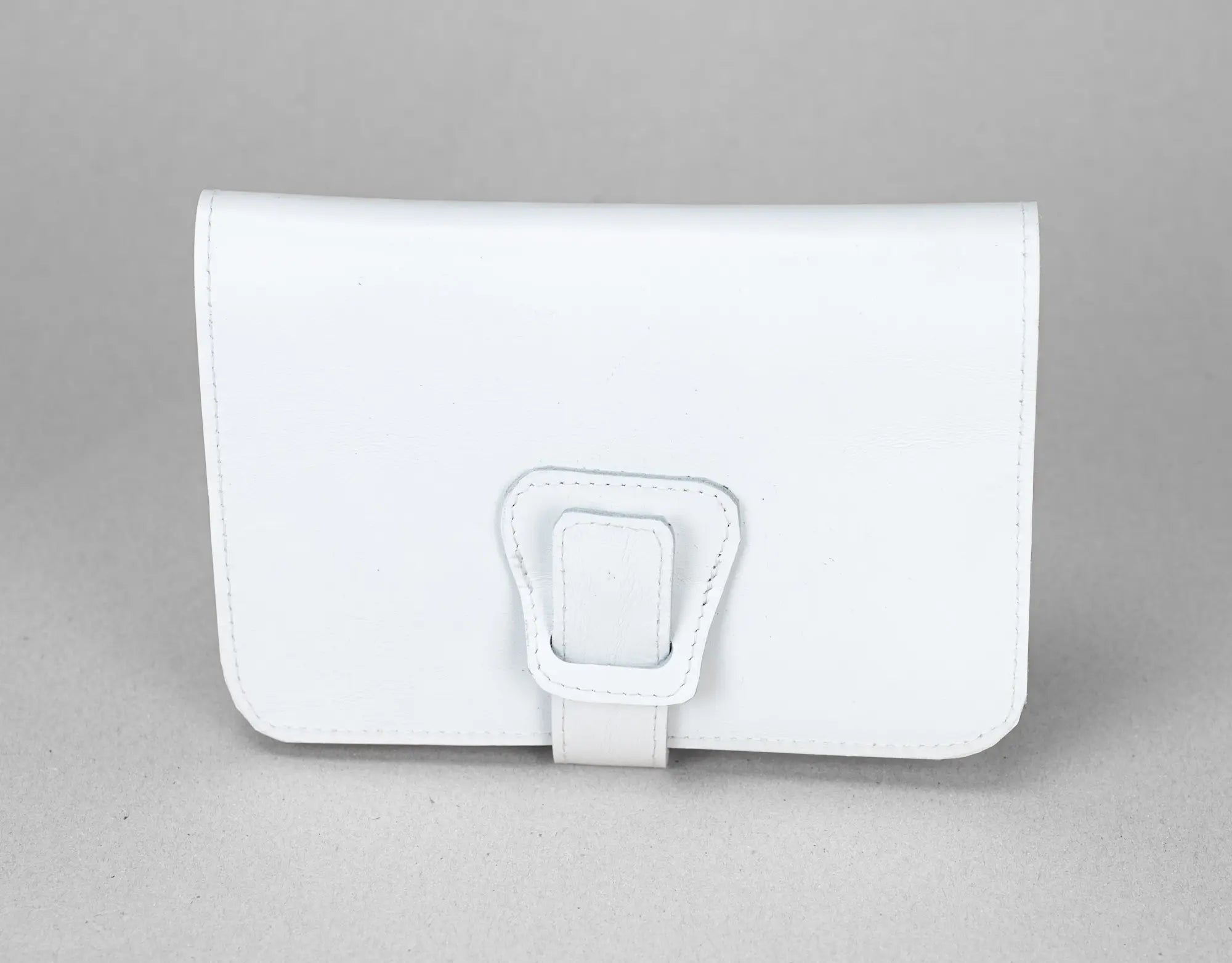 White leather wallet with a buckle on a gray background