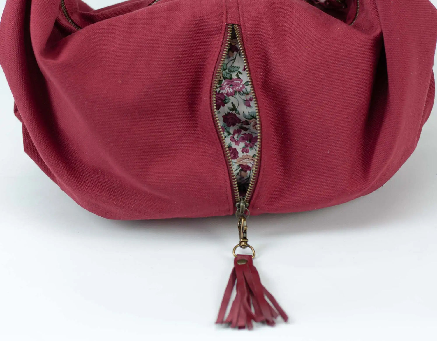 Red handbag with floral zipper pull on a white background