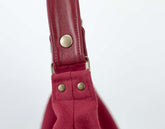 Close-up of a red bag strap with gold hardware on a white background